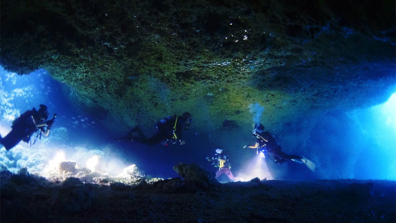 水中ライトで照らしながら海底洞窟を進む